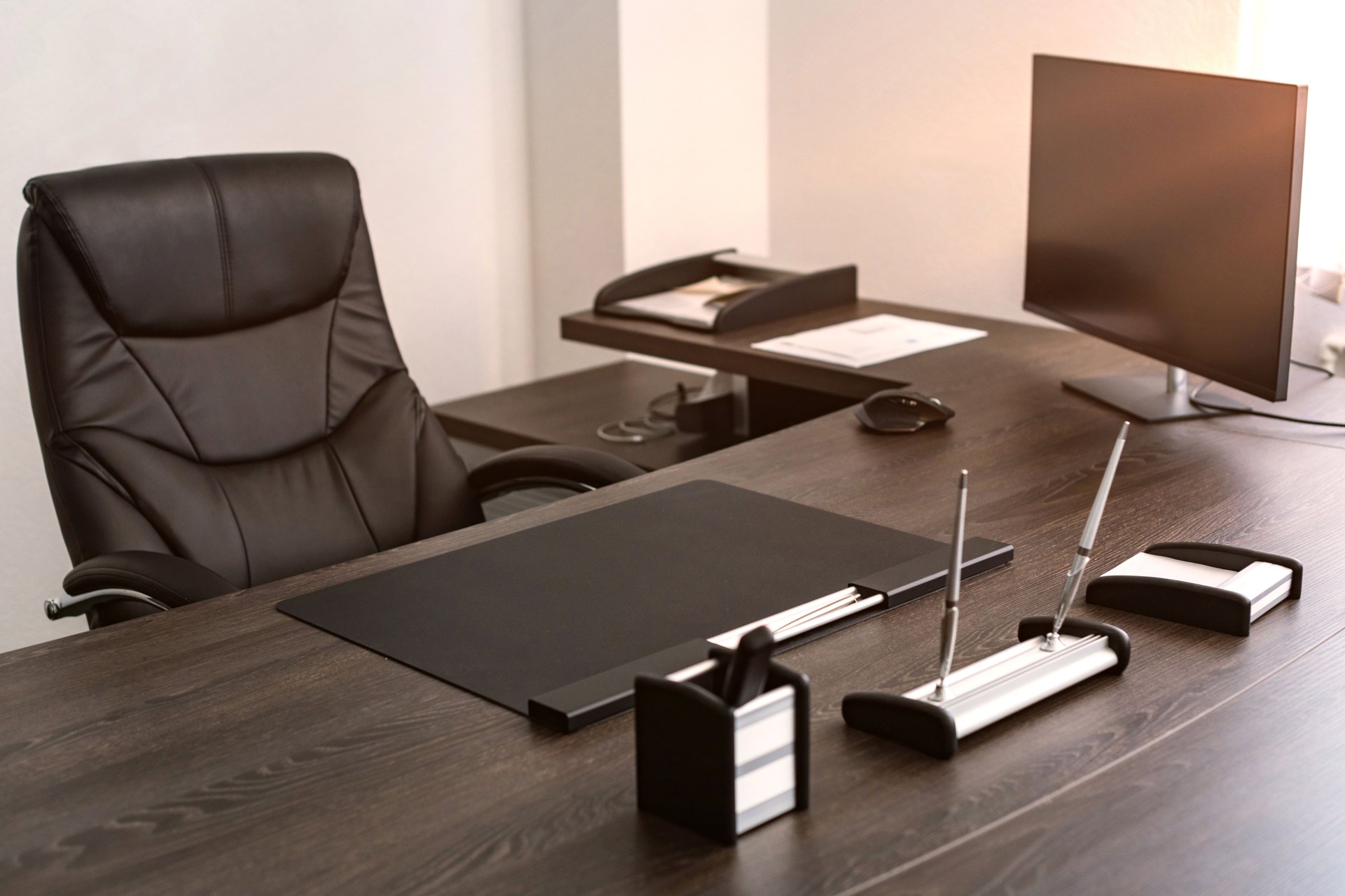 Workplace of chief of company: leather chair, writing instruments, monitor.